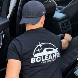 Baptiste, de dos, en train d'aspirer la banquette arrière d'une voiture